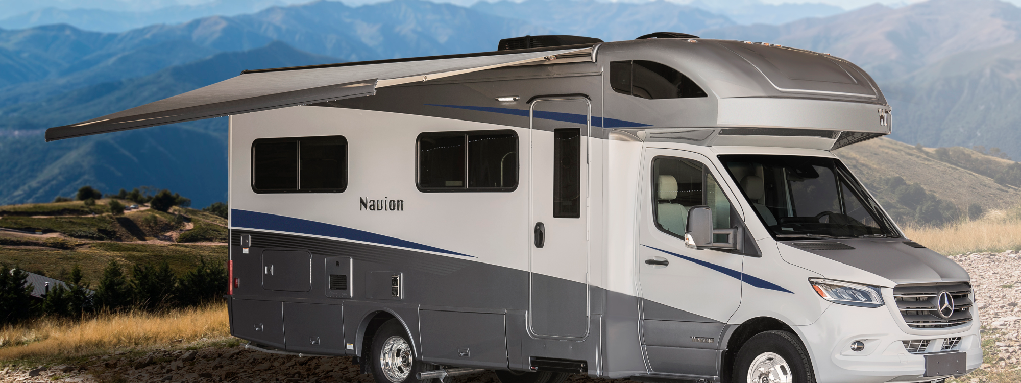 Winnebago Navion with the awning extended on a hilltop